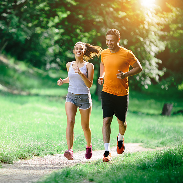 Man and a woman dressed in jogging clothes running through the park